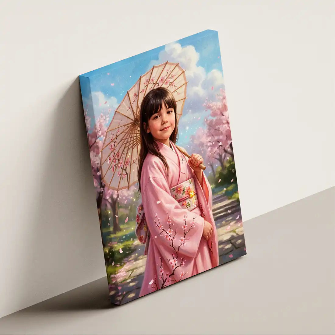 A vertical canvas wall art print leaning against a light gray wall. The artwork depicts a young girl in a pink kimono holding a pink cherry blossom parasol under a blue sky with clouds, with pink cherry blossom trees in the background.