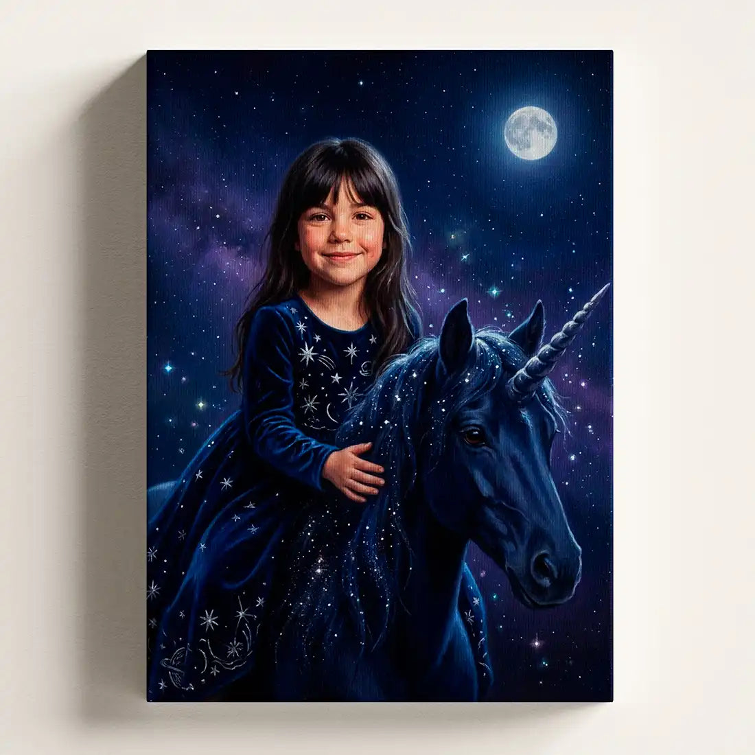 A vertical canvas wall art print depicting a young girl in a starry navy dress riding a dark unicorn under a full moon, shown hanging on a light beige wall.