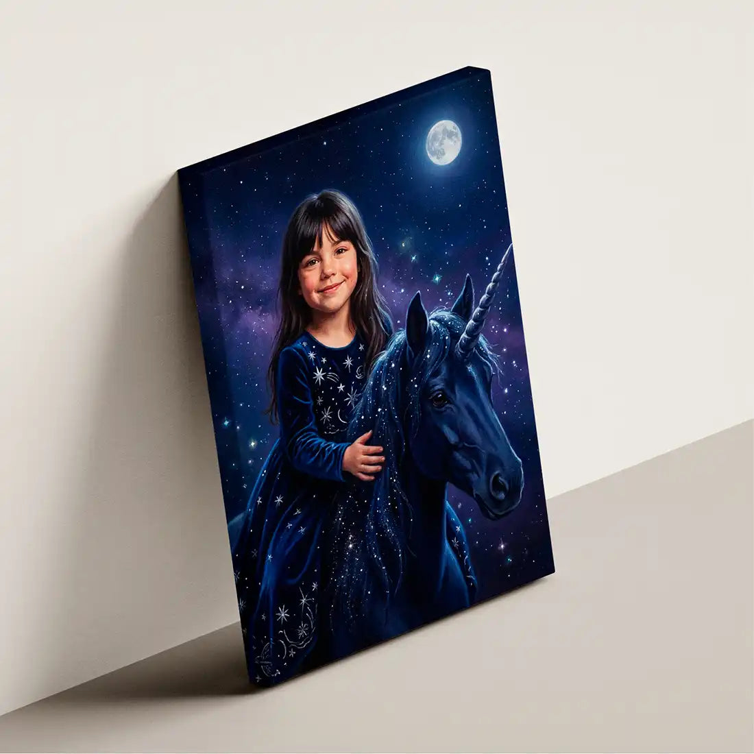 A rectangular canvas wall art print leaning against a light beige wall on a matching floor. The artwork shows a young girl in a starry blue nightgown smiling beside a dark unicorn under a full moon.