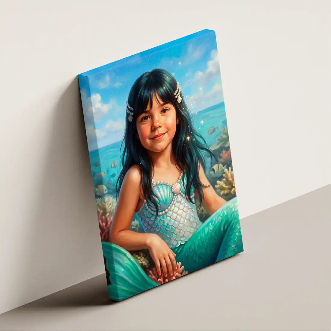 A rectangular canvas wall art print leaning against a light gray wall on a gray floor. The artwork shows a young girl with long dark hair sitting on an ocean reef, wearing a blue-green mermaid tail and shell top, with blue water and sky in the background.