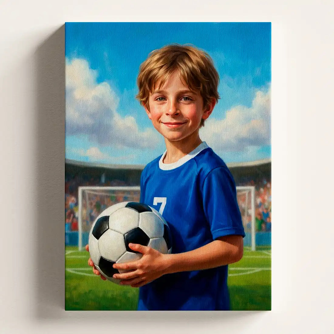 A vertical canvas wall art print depicting a young boy smiling and holding a soccer ball on a green field under a blue sky, shown hanging on a light gray wall.